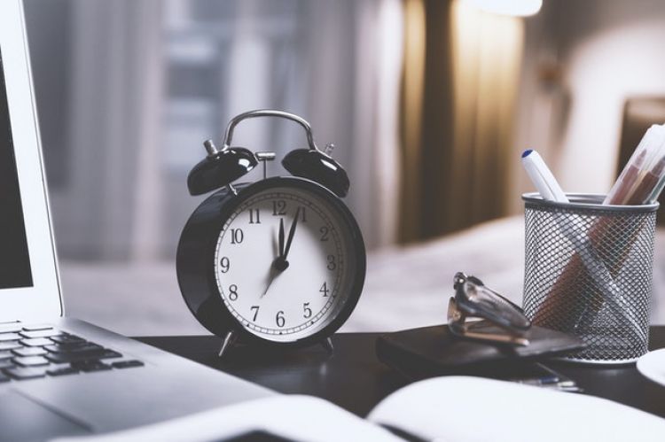 Analog clock next to laptop