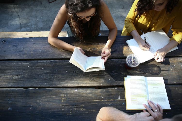 A group of three people reading and taking notes