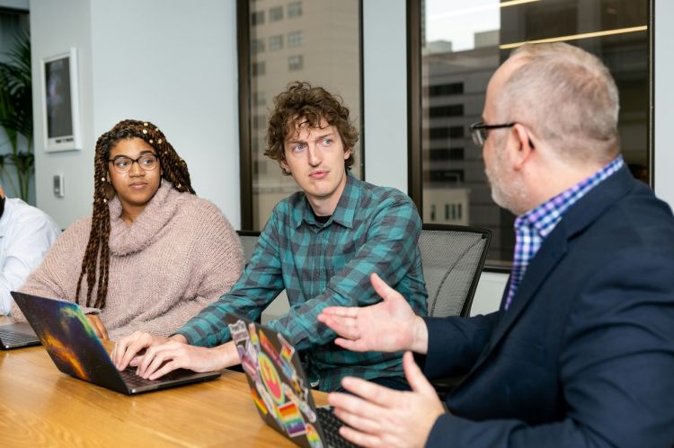 three people talking in a meeting room
