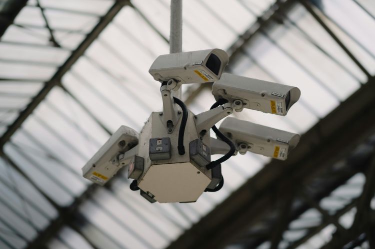 Closeup of four security cameras hanging from the ceiling.
