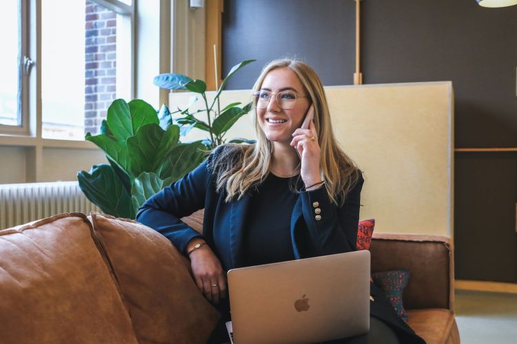 a woman talking on the phone while holding a Macbook