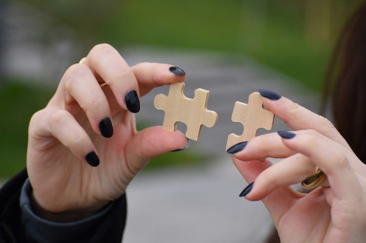 a person connecting two wooden puzzle pieces