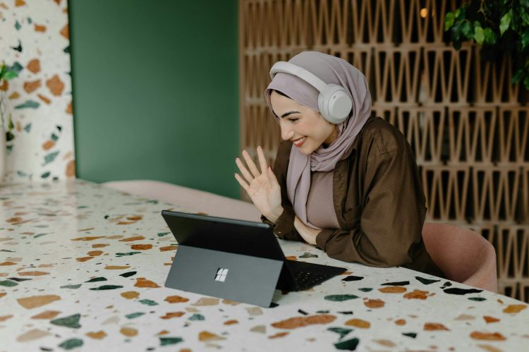 A woman waving on a remote meeting