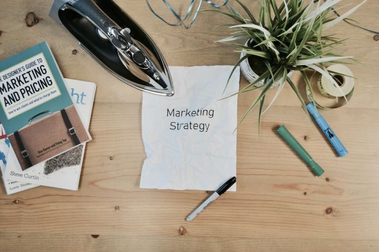 Overhead shot of a desk with office supplies and a white paper with "Marketing Strategy" printed on it.