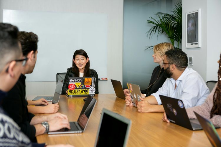people in a meeting on laptops, sitting at a conference table