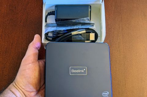 The Beelink U59 Pro in my hand along with packaging and accessories