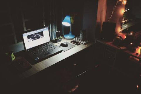 Laptop and computer desk in a dimly lit room. Image provided by Pexels: https://www.pexels.com/photo/black-laptop-beside-black-computer-mouse-inside-room-669996/