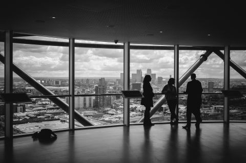 Business professionals meeting near a large window in a tall building overlooking a city.