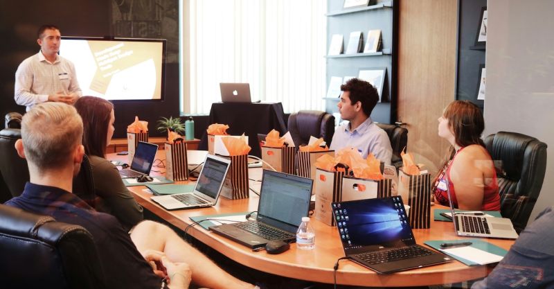 a group of people on laptops around a conference table at a business meeting