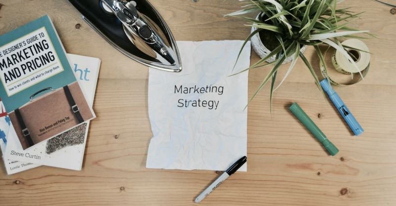Overhead shot of a desk with office supplies and a white paper with "Marketing Strategy" printed on it.