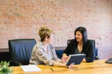 two women talking, sitting at a conference table