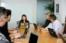 people in a meeting on laptops, sitting at a conference table
