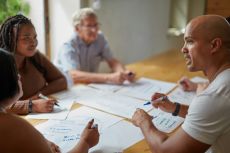 people sitting around a conference table writing on papers